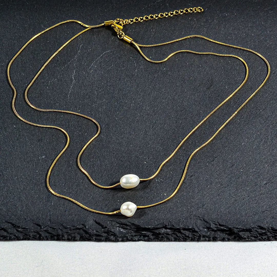 Goldene Perlenkette auf schwarzem Schiefer.