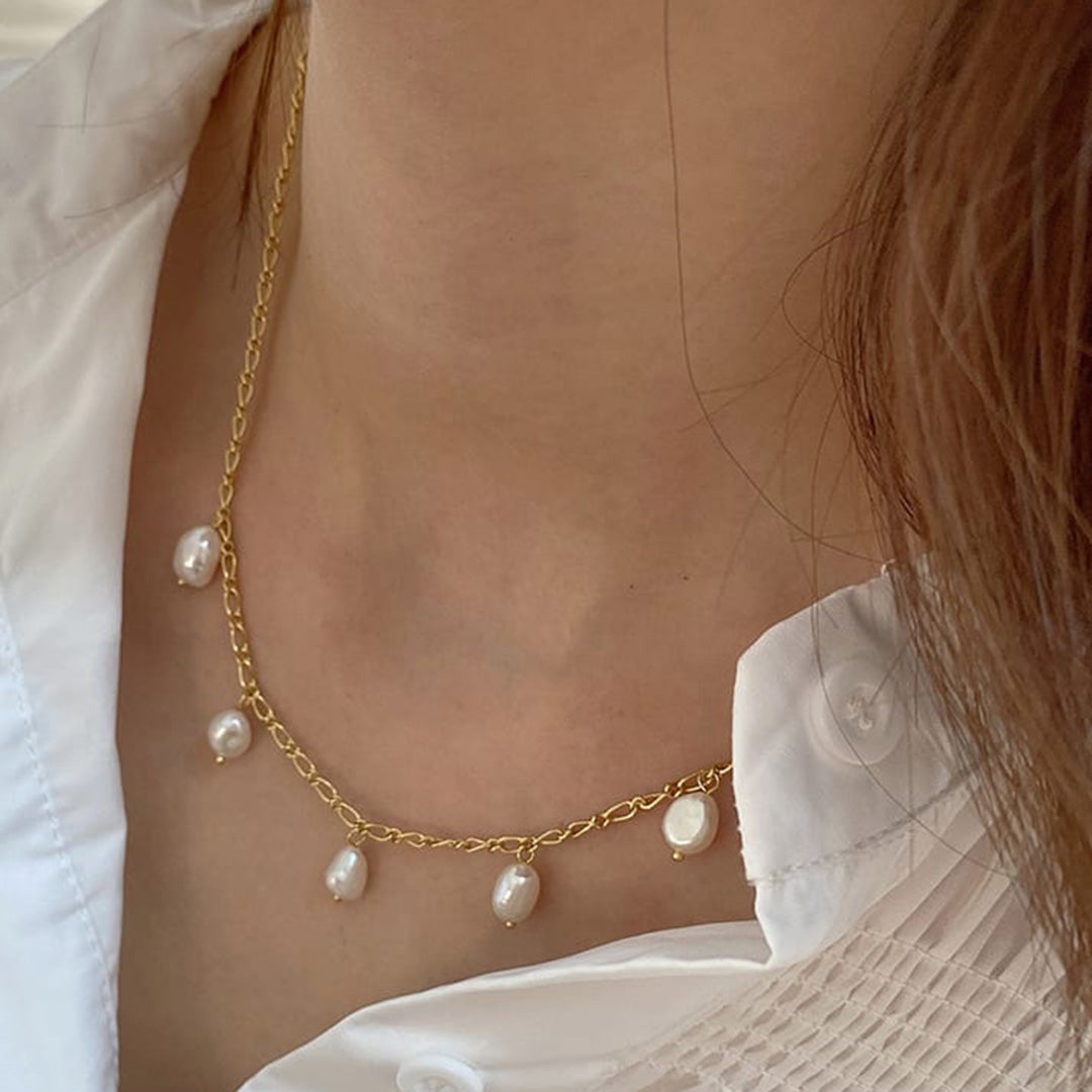 Ein Model trägt eine Silber Halskette in Farbe Gold um den Hals. Die zauberhafte Silberkette besitzt fünf Perlen.