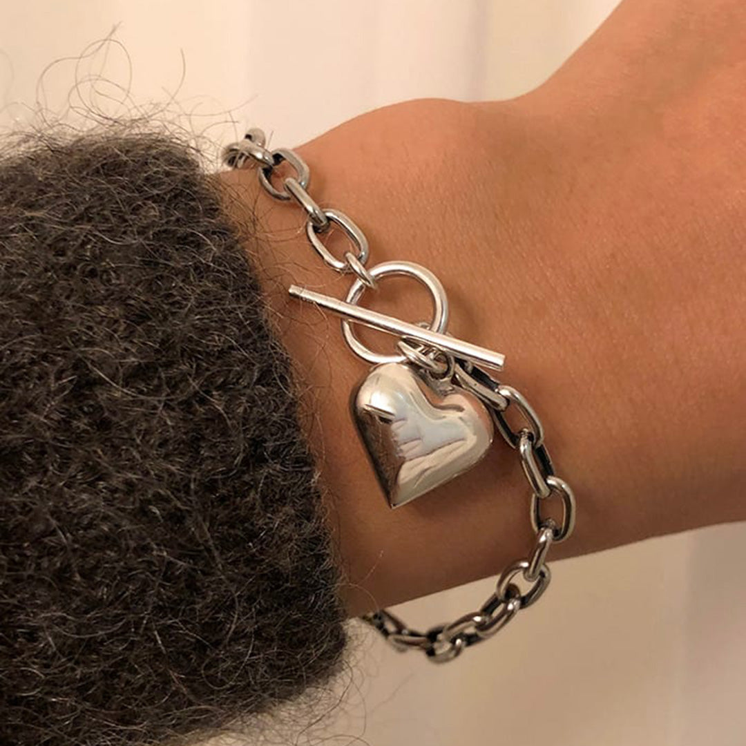 Silber am Handgelenk eines Models. Sie zeigt ein Silber Armband mit einem Silber Herz Anhänger von dem Onlineshop für Damen und Herren Schmuck 1887Gem.com
